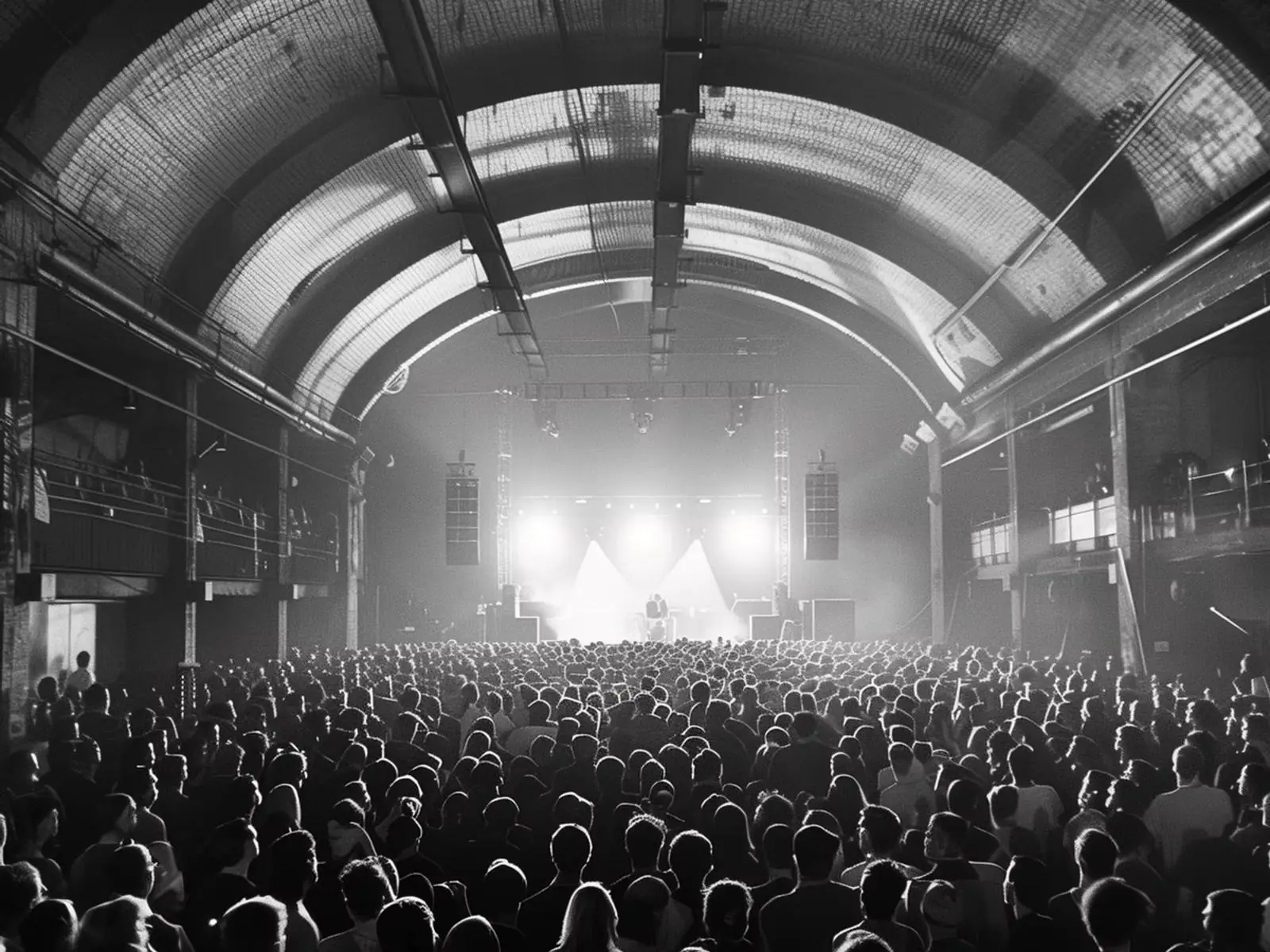 Crowd facing a lit stage in a packed live venue